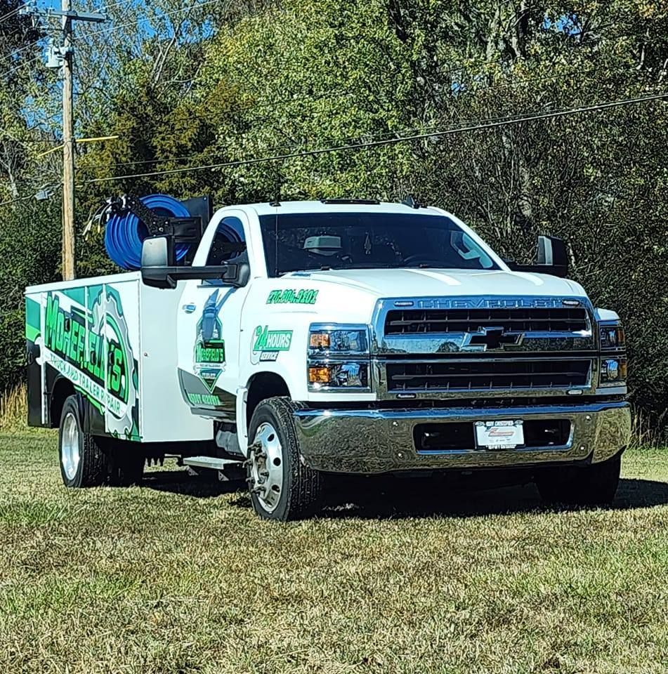A white tow truck is parked in a grassy field.