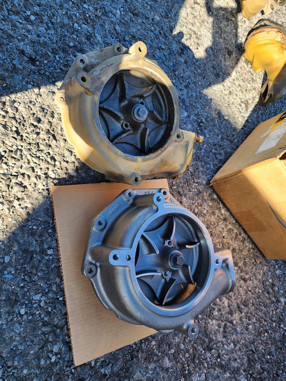 Two water pumps are sitting on top of a cardboard box on the ground.