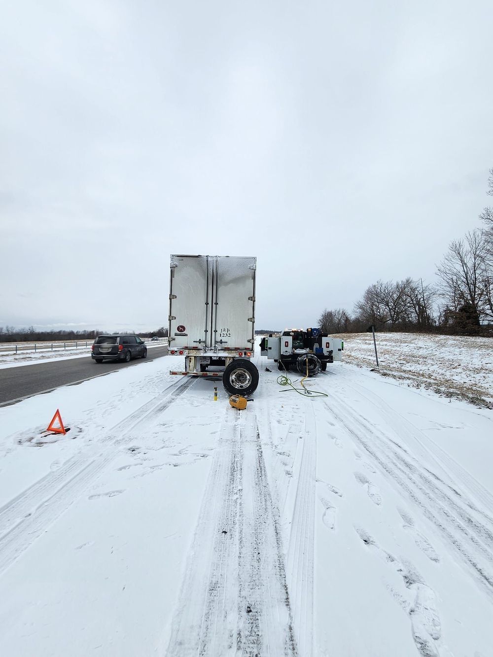 A truck is stuck in the snow on the side of the road.