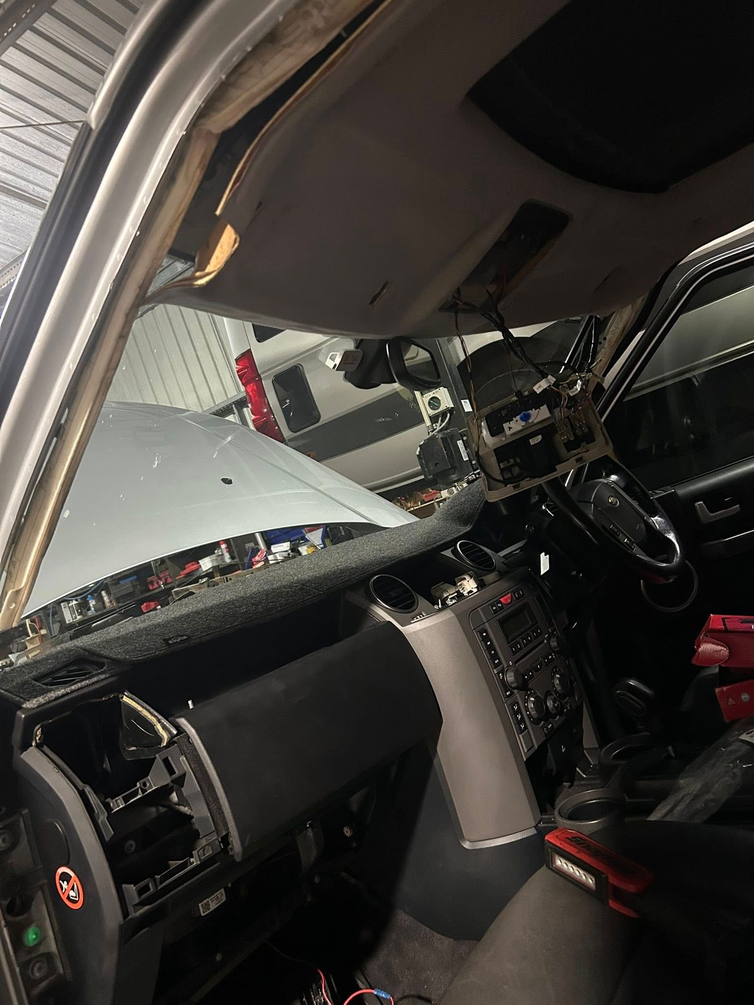 Interior of a vehicle with dashboard components exposed; mechanic's view in a garage.