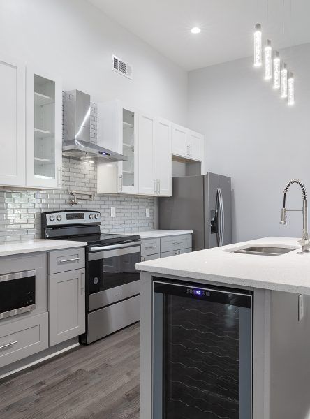 Modern kitchen with white cabinets, stainless steel appliances, and a gray island.