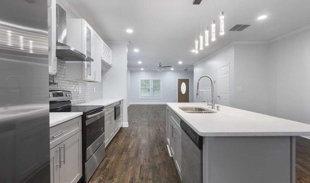 Row of white cabins with glass windows and small patios; trees and grass in the background.