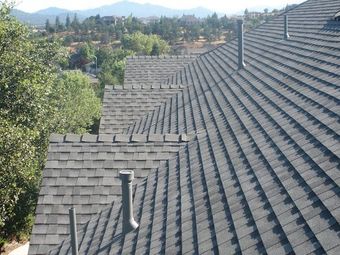 A row of roofs with trees and mountains in the background