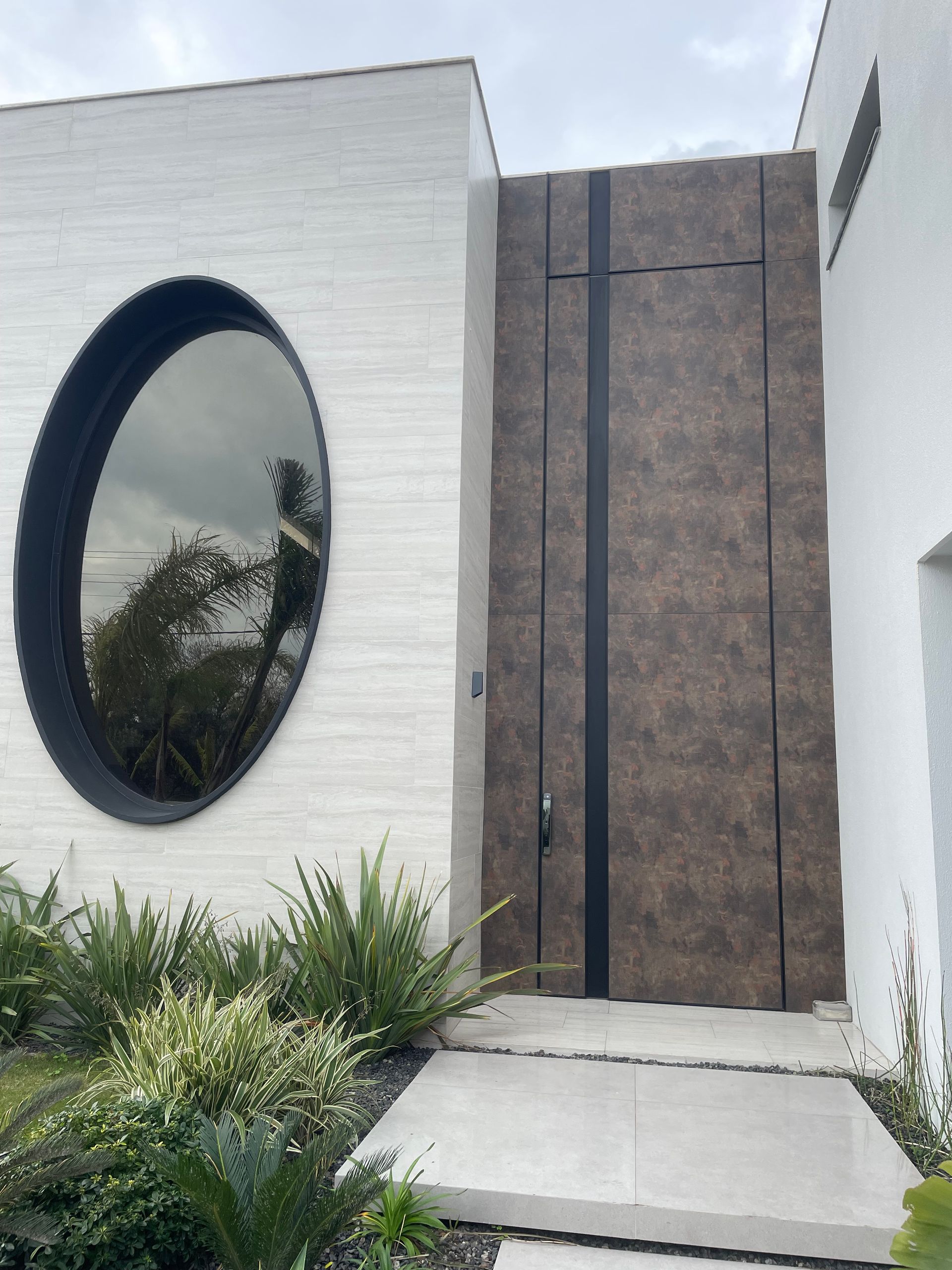 A white house with a brown door and a round window