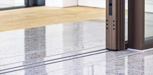 A close up of a sliding glass door on a marble floor.