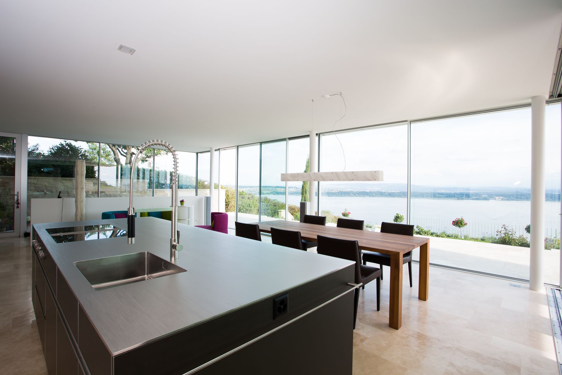 A kitchen with a large island and a dining table with a view of a lake.