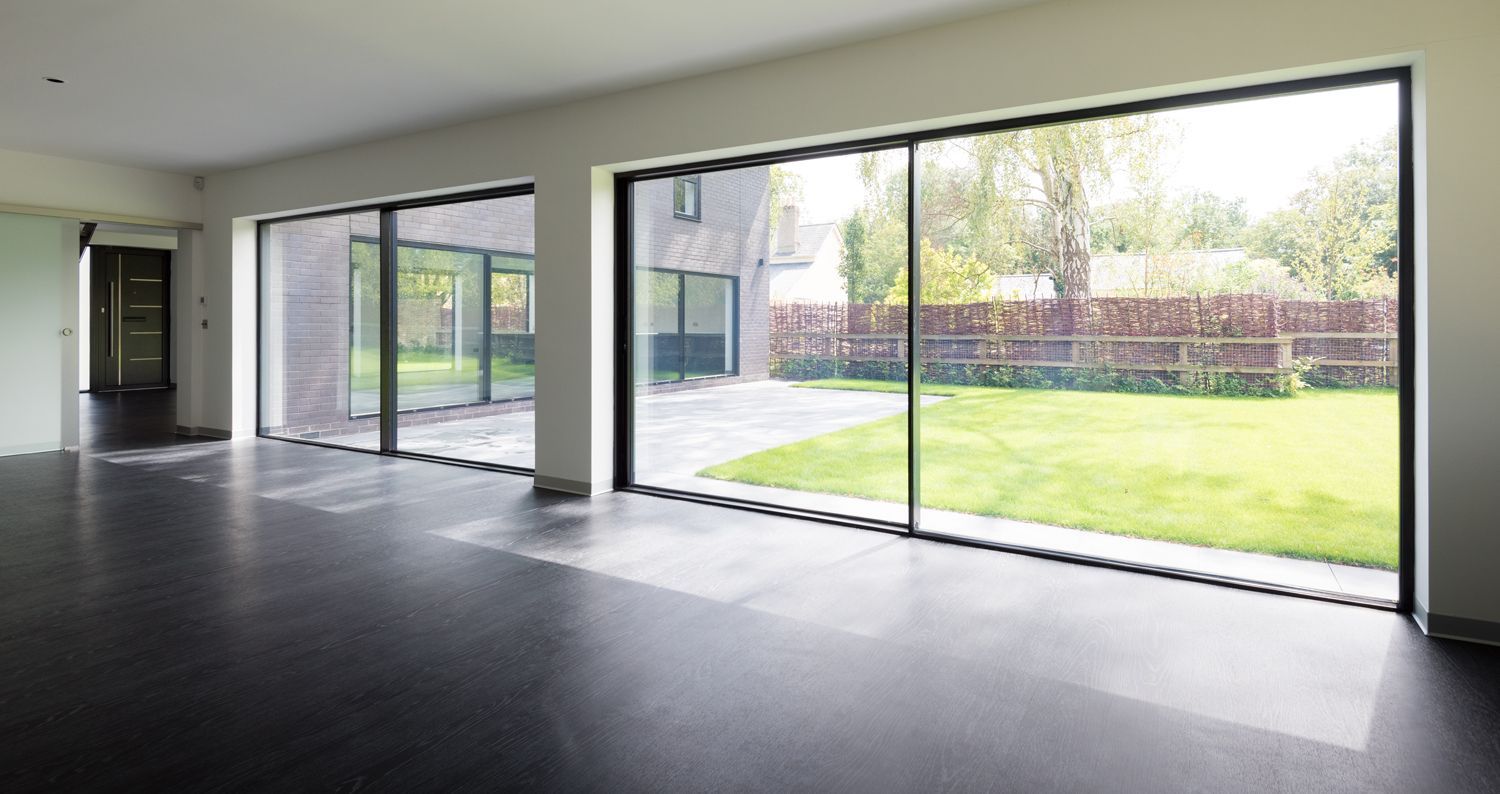 An empty room with a lot of windows and a view of a garden.