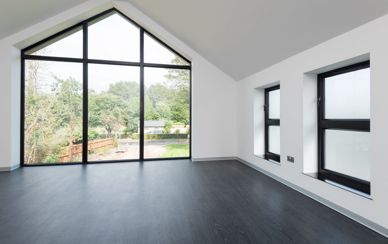 An empty room with a lot of windows and a black floor.