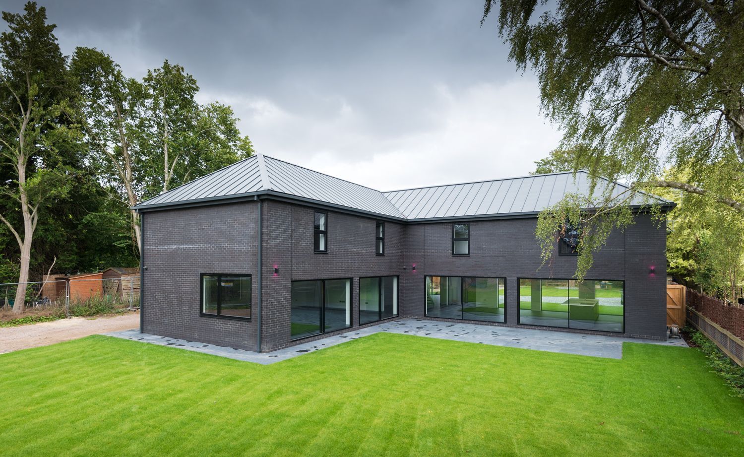 A large black brick house with a large lawn in front of it.