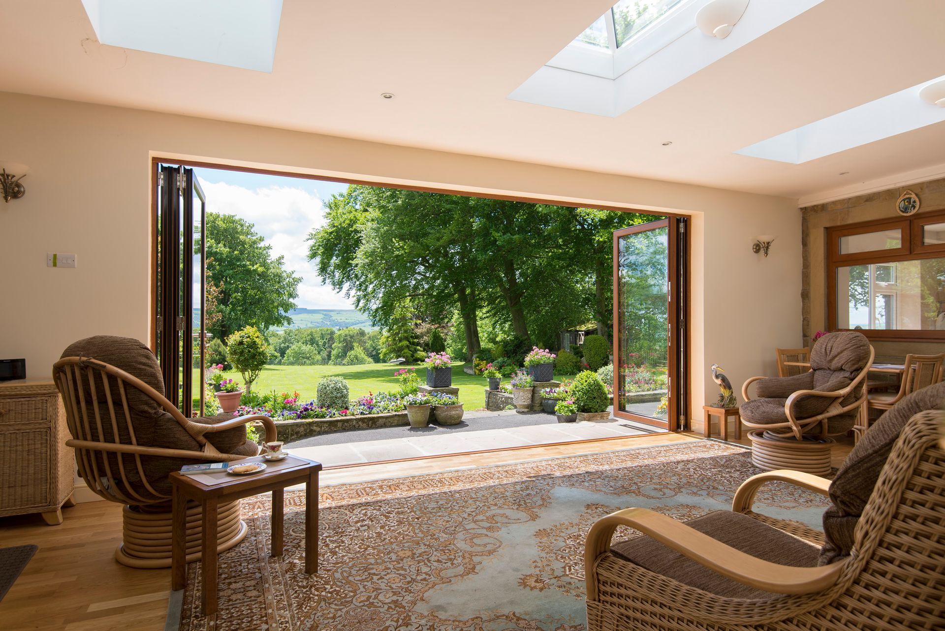 A living room with wicker furniture and a view of a garden.