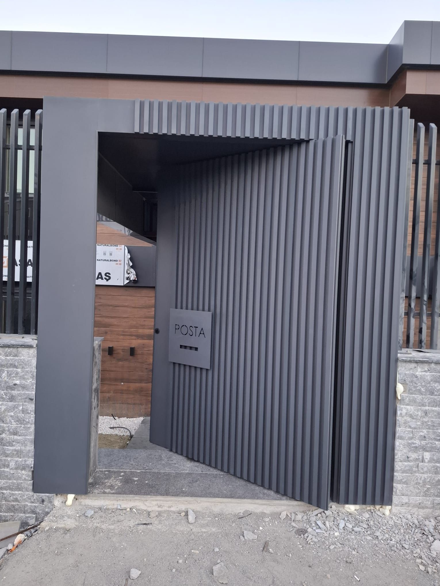 A black gate is open and leading to a building.