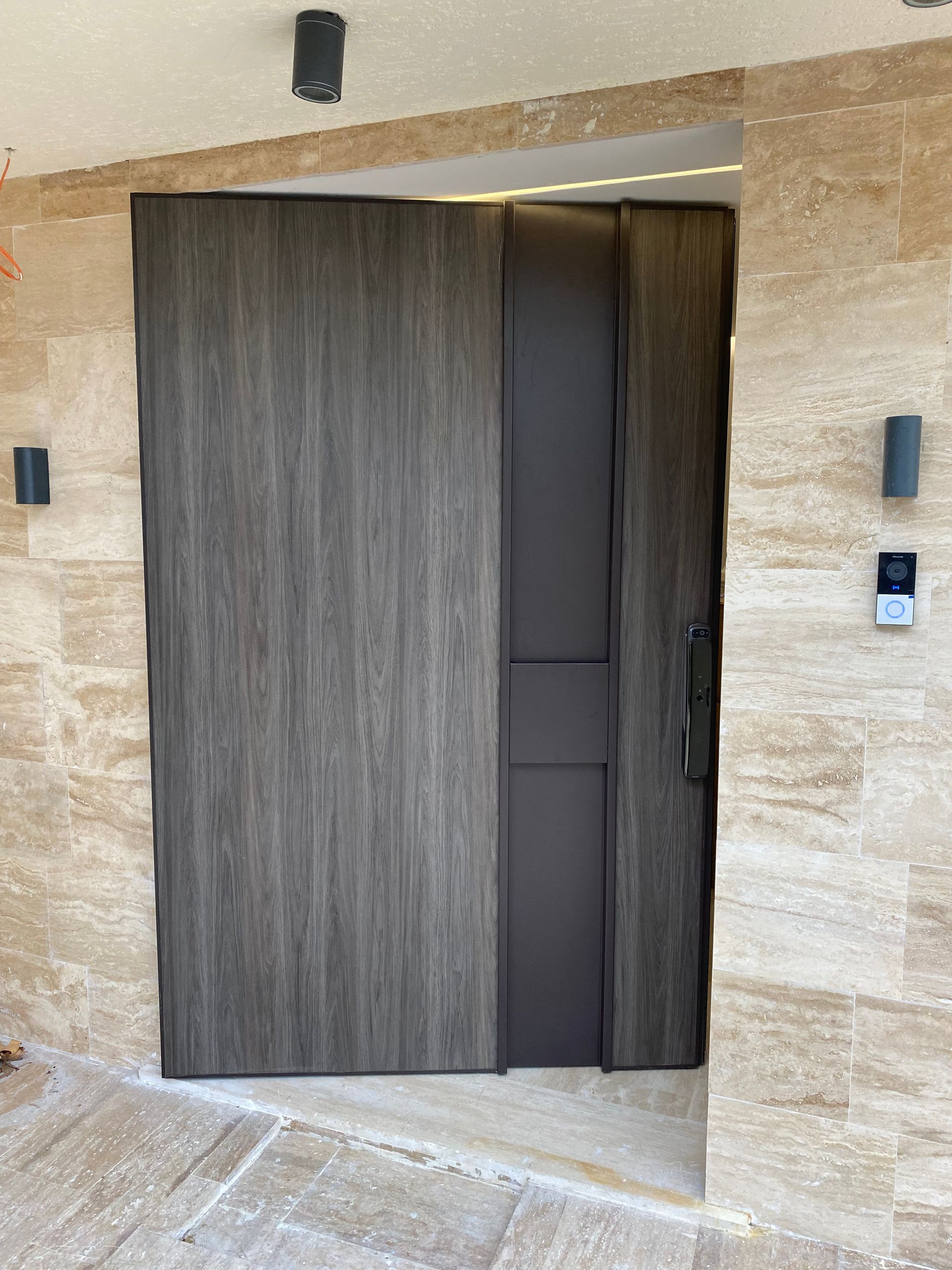 A large wooden door is sitting in front of a stone wall.