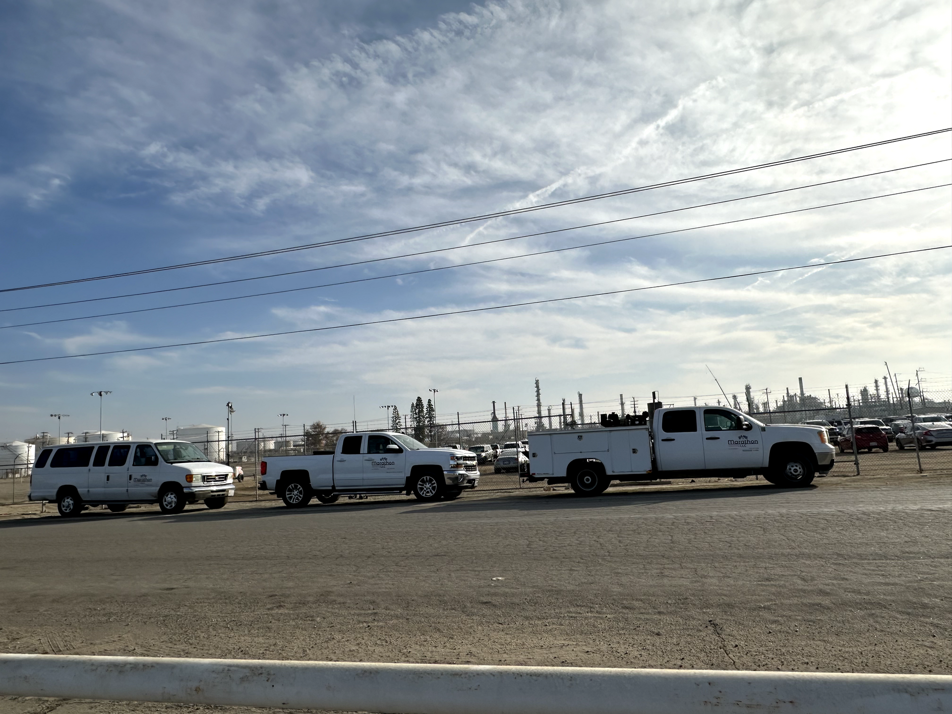 A row of white trucks are parked on the side of the road
