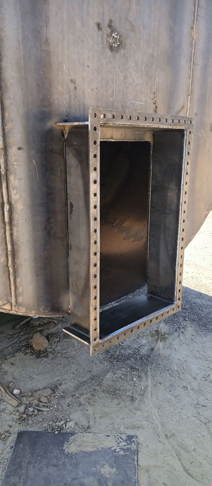 A Metal Box Is Sitting on The Ground Next to A Metal Wall.