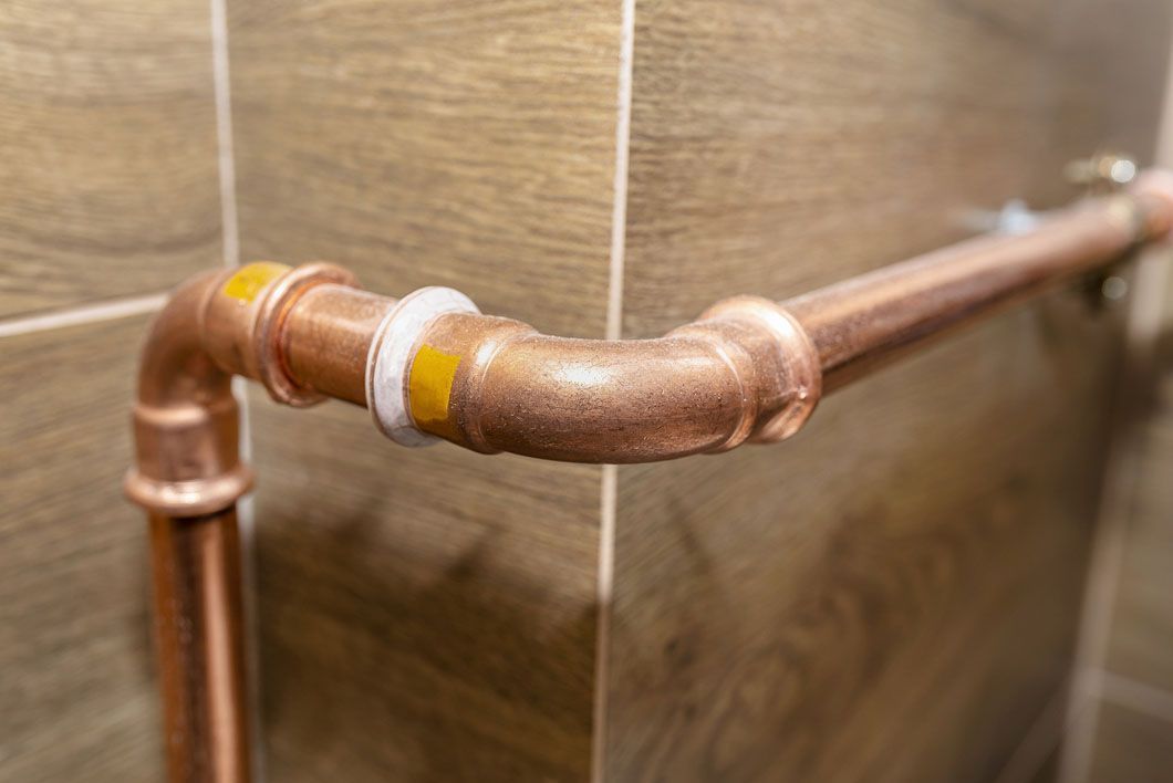 A close up of a copper pipe in a bathroom.