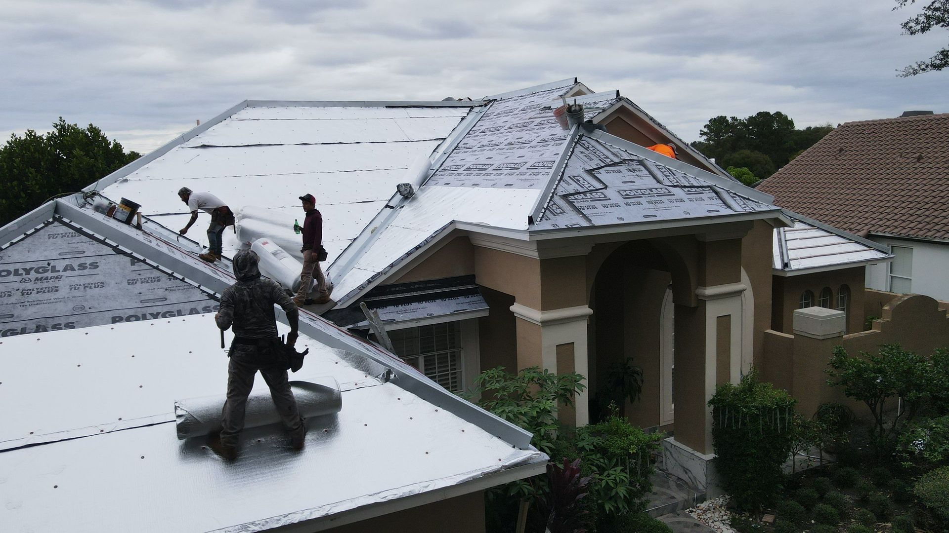 Damaged asphalt shingle roof, missing shingles exposing black underlayment; overcast sky.