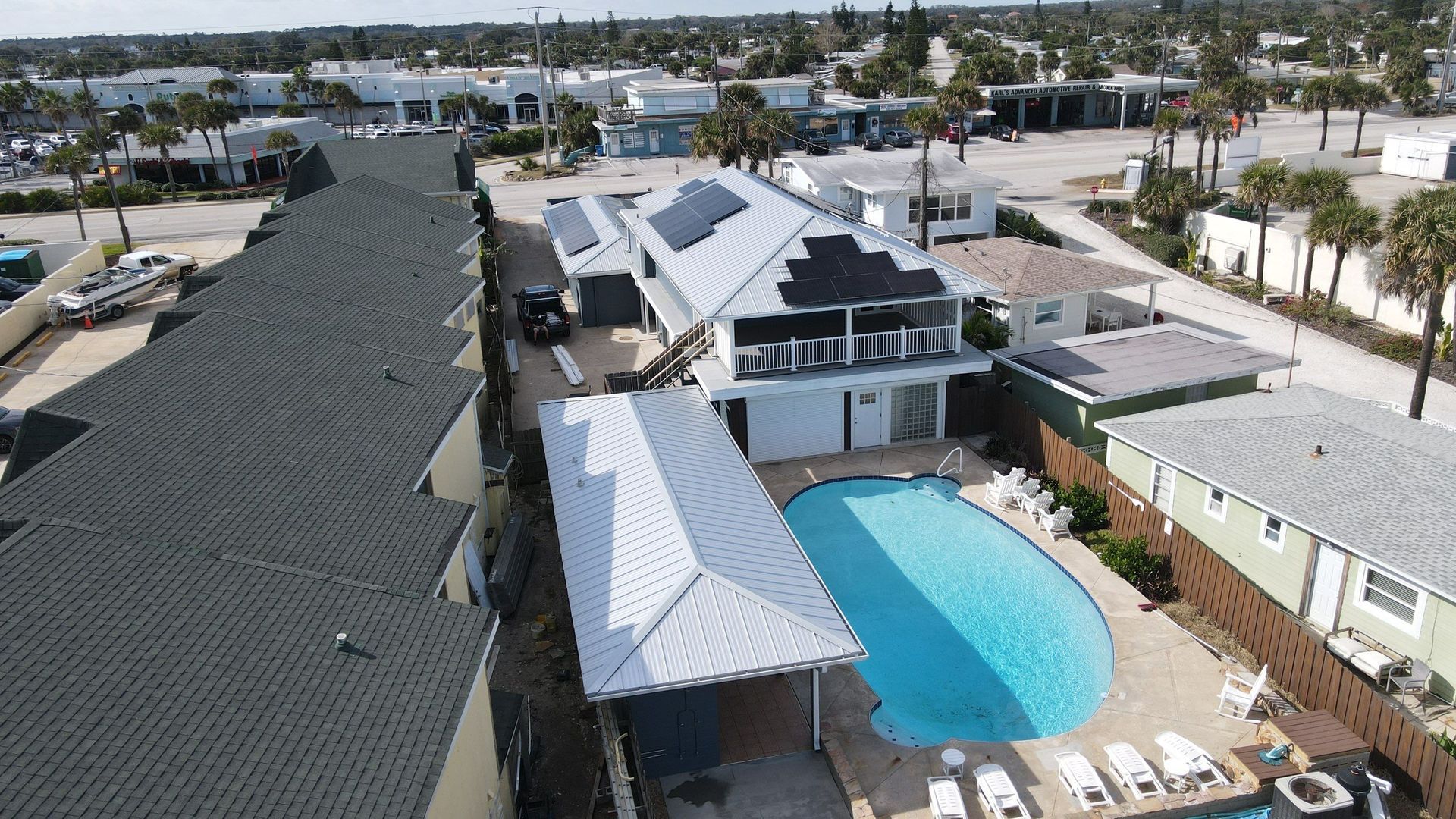 Roofers installing shingles on a yellow house roof, using safety harnesses.