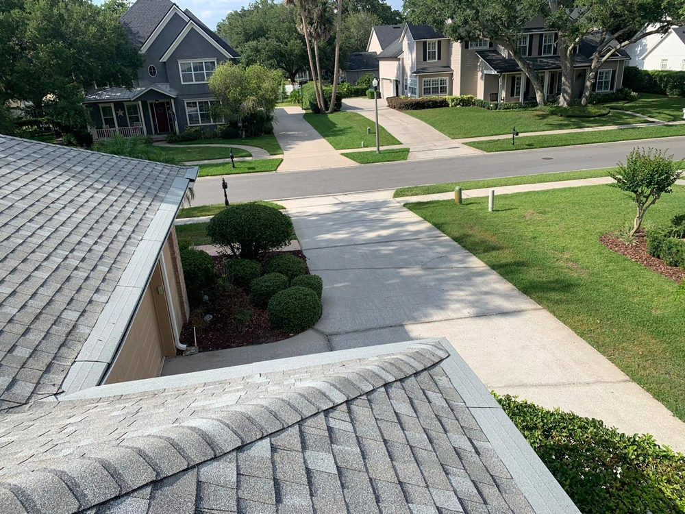 View from a roof of a residential street with houses, sidewalks, driveways, and greenery.