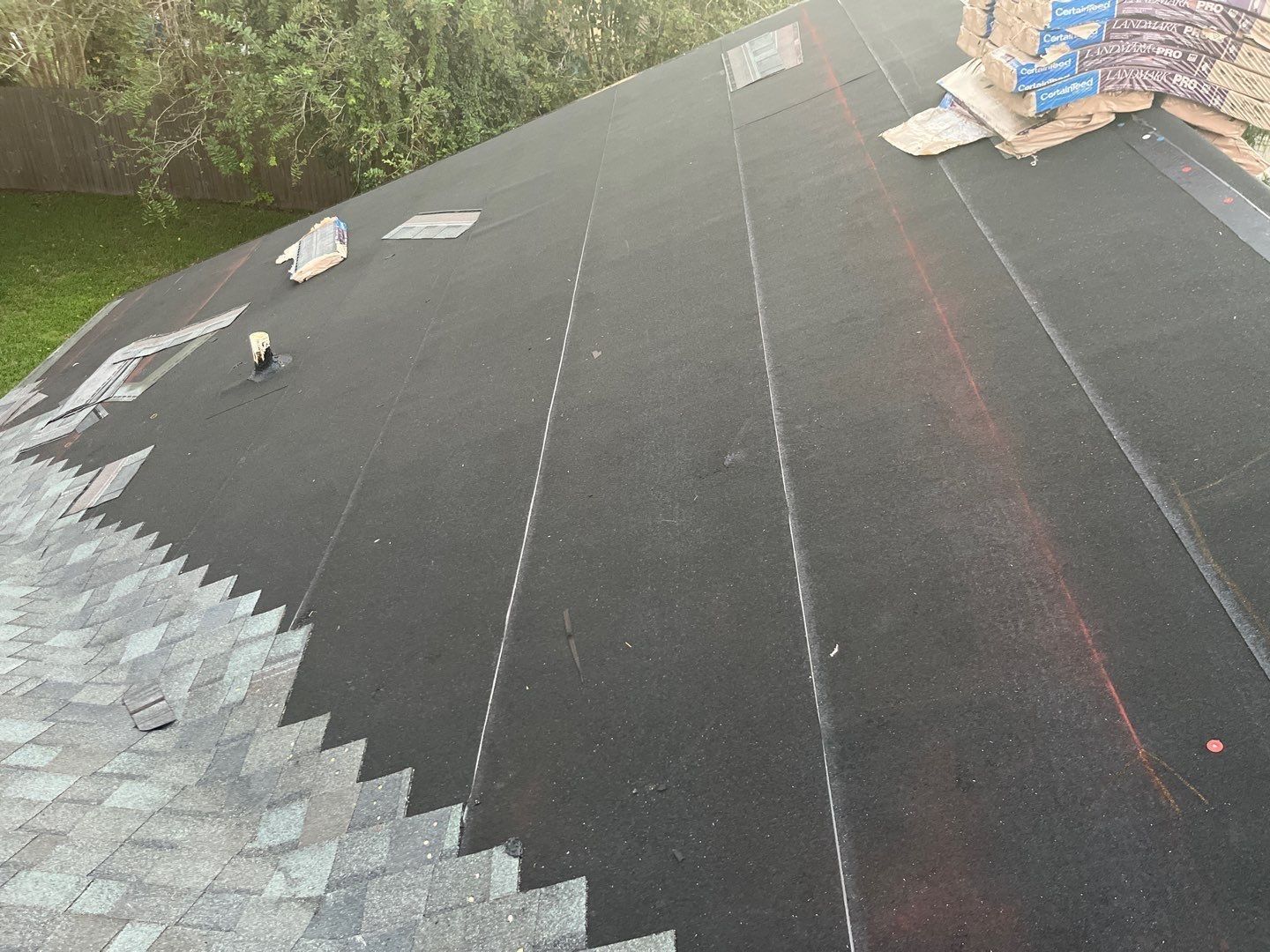 Roof partially covered with new grey shingles; other areas are still being worked on.