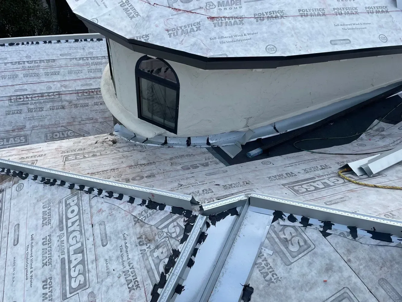 Roof of a building being worked on with protective paper and metal flashing around a window.
