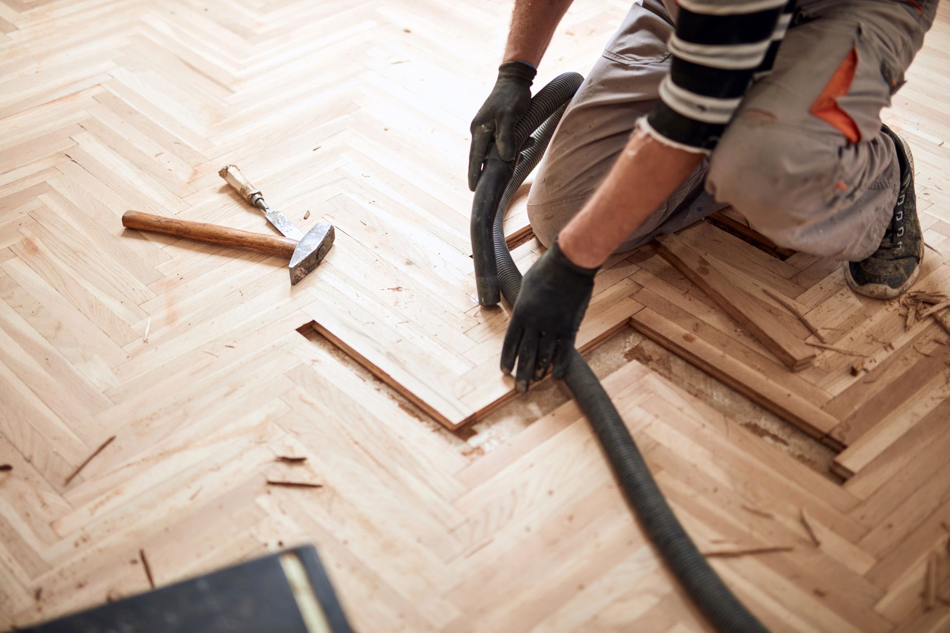 A man is cleaning a wooden floor with a vacuum cleaner.
