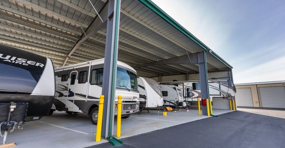 Recreational vehicles parked under a metal roof shelter; sunny day.