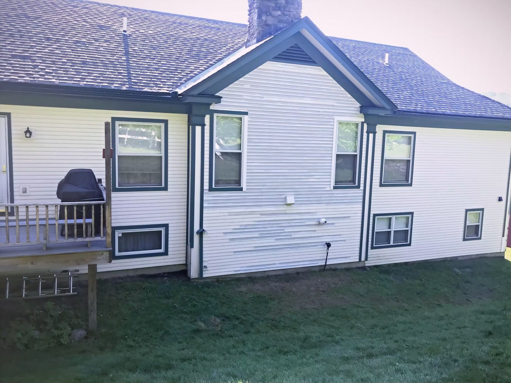 A white house with a blue roof and a deck