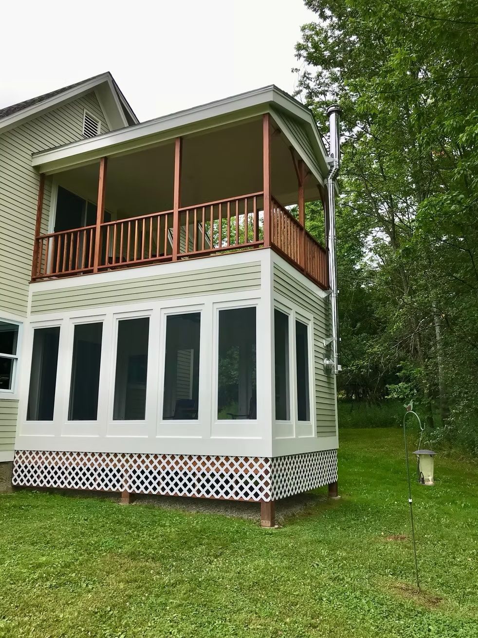A house with a screened in porch and a balcony.