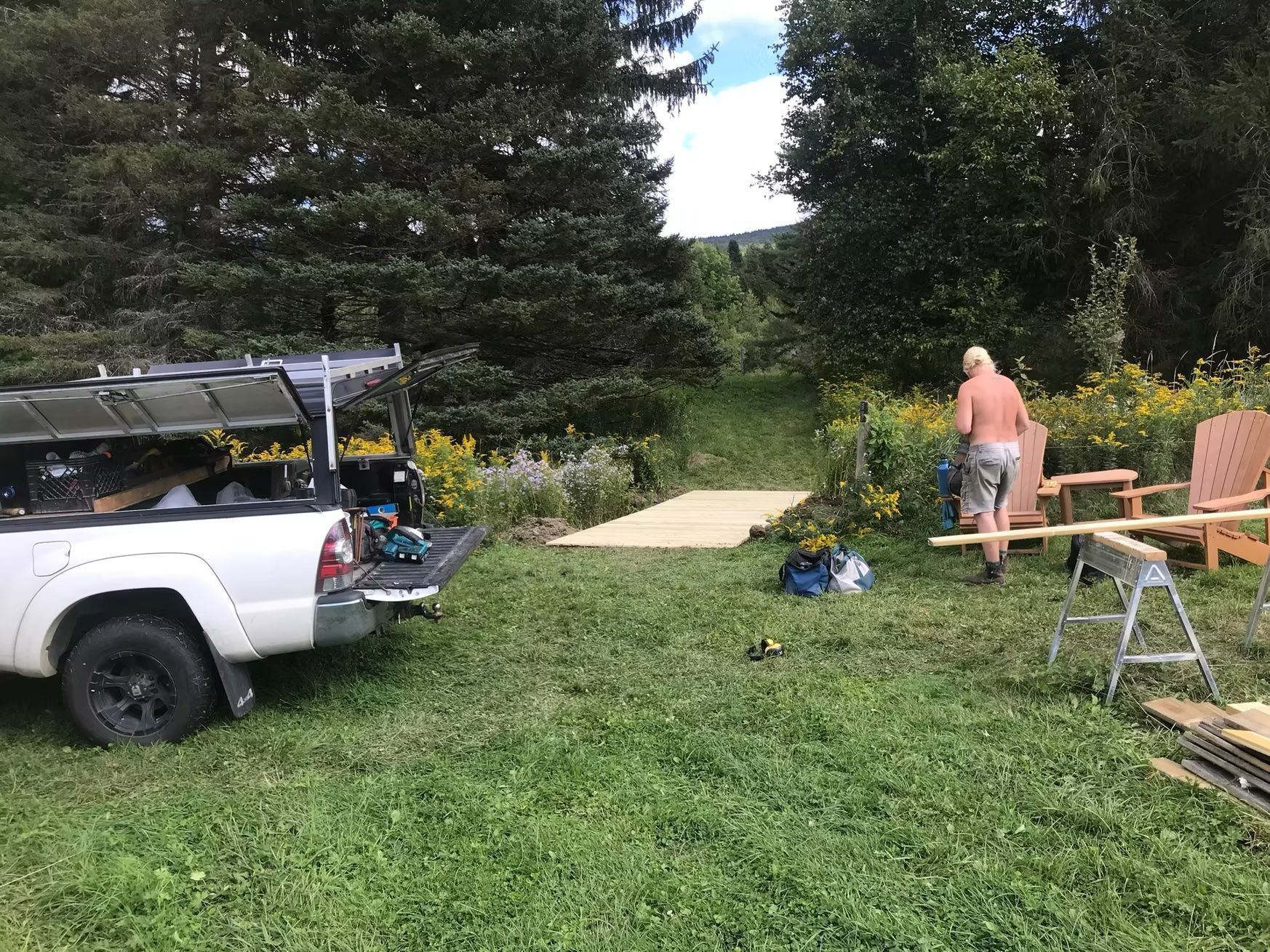 A man standing next to a truck in a grassy field.