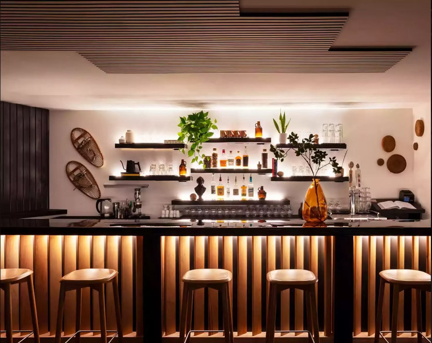 A bar with stools and bottles on shelves