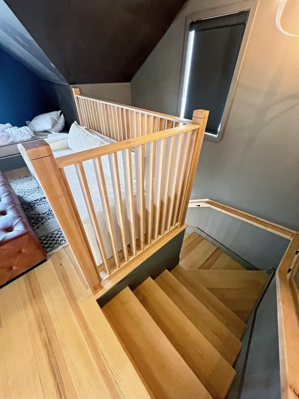 A wooden staircase leading up to a bedroom with a wooden railing.