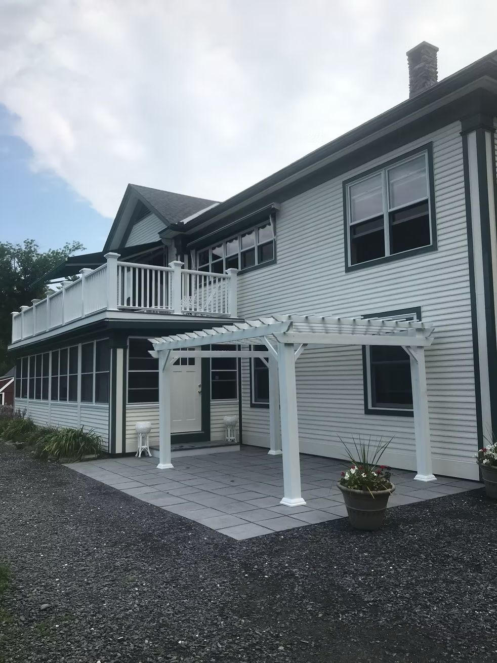 A white house with a pergola on the side of it