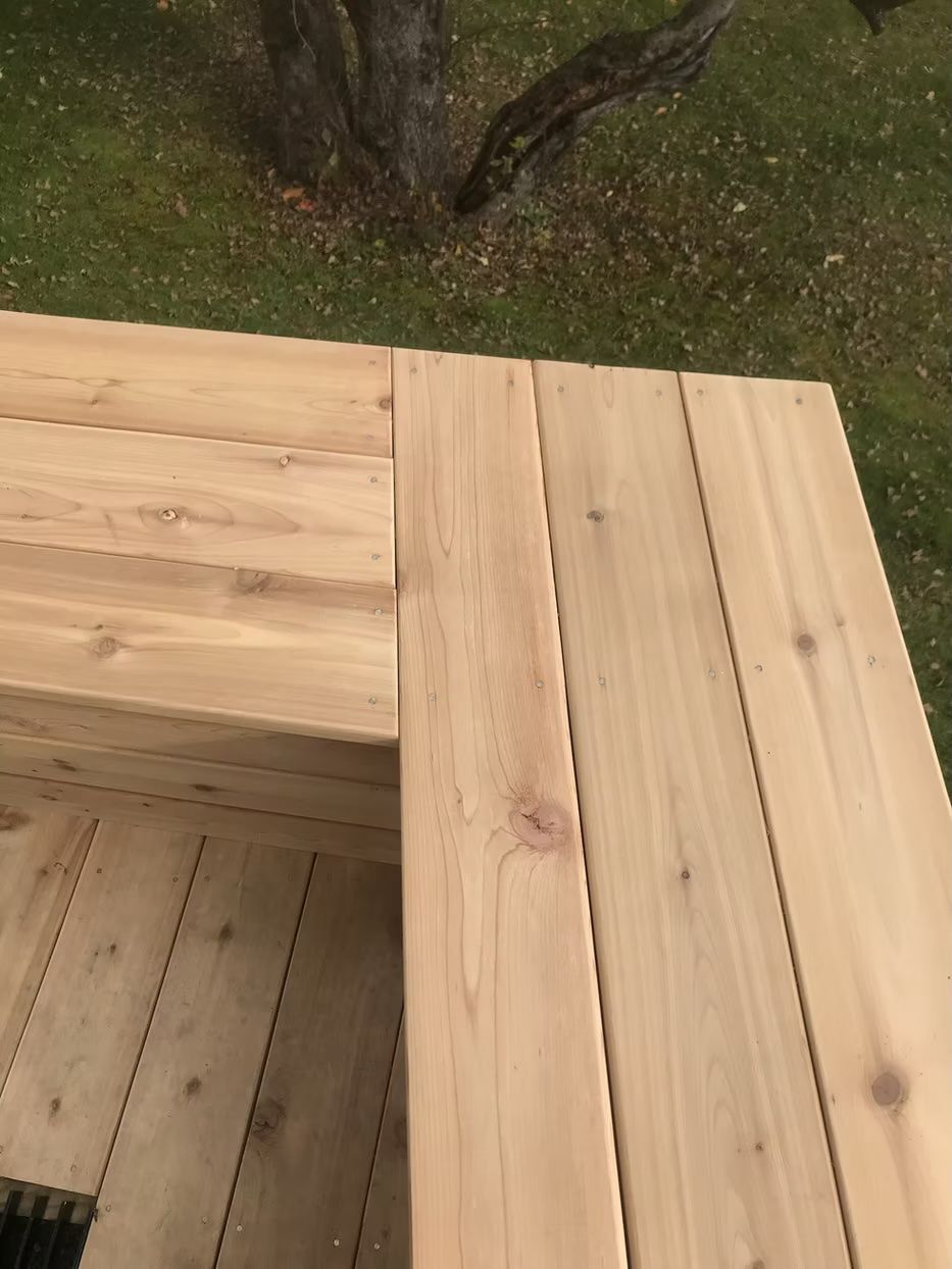 A close up of a wooden deck with a tree in the background.