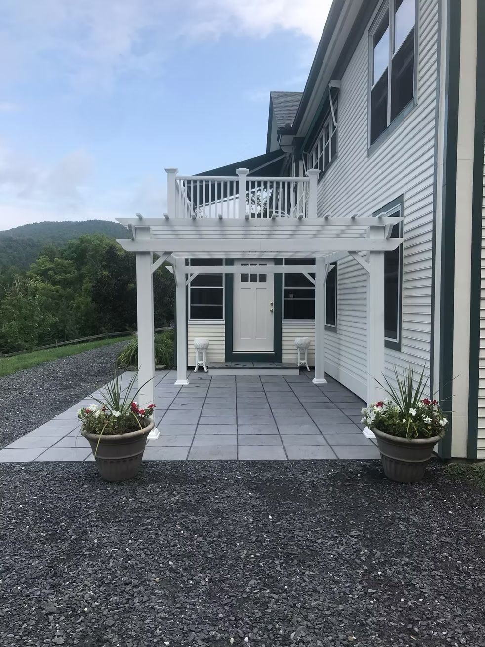 A white house with a pergola and a balcony on top of it.