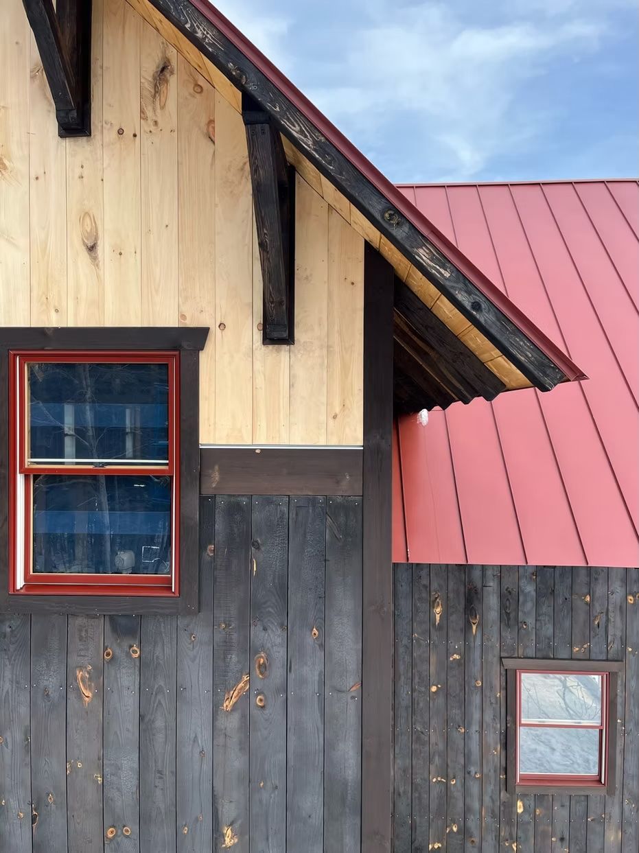 A wooden house with a red roof and a window