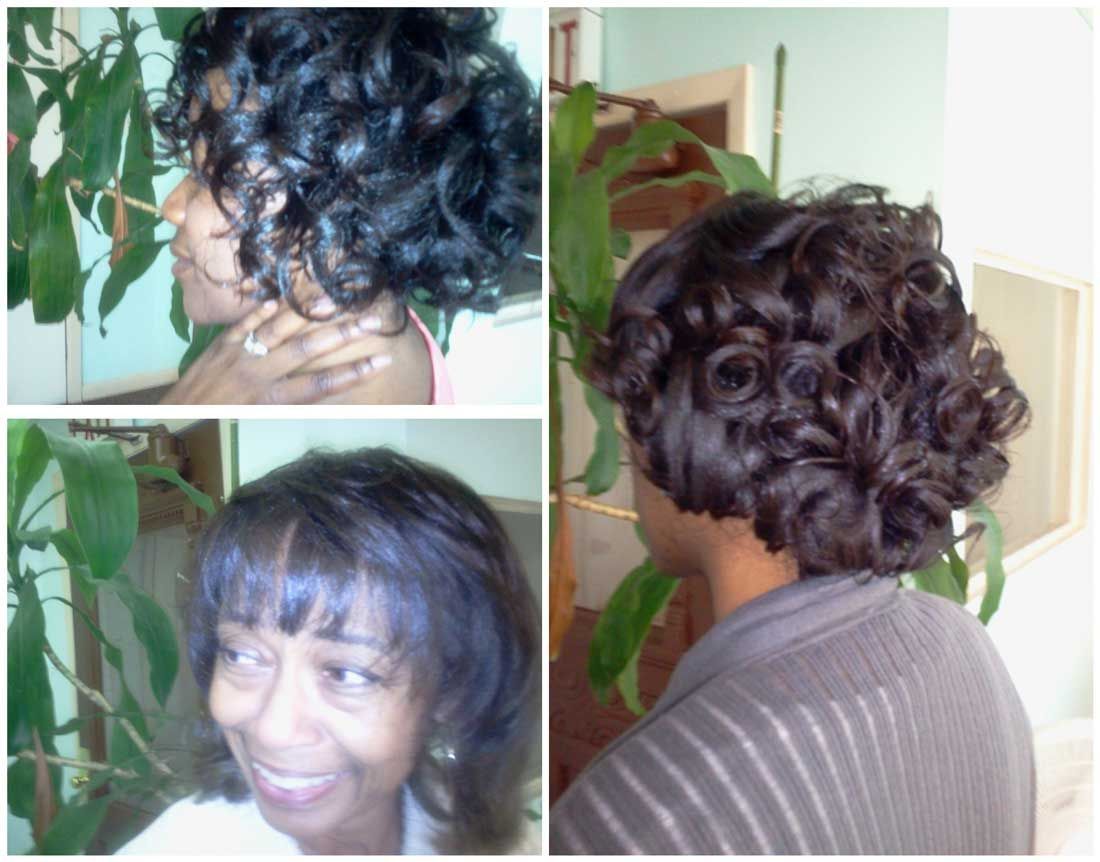 A woman with curly hair is smiling in front of a plant