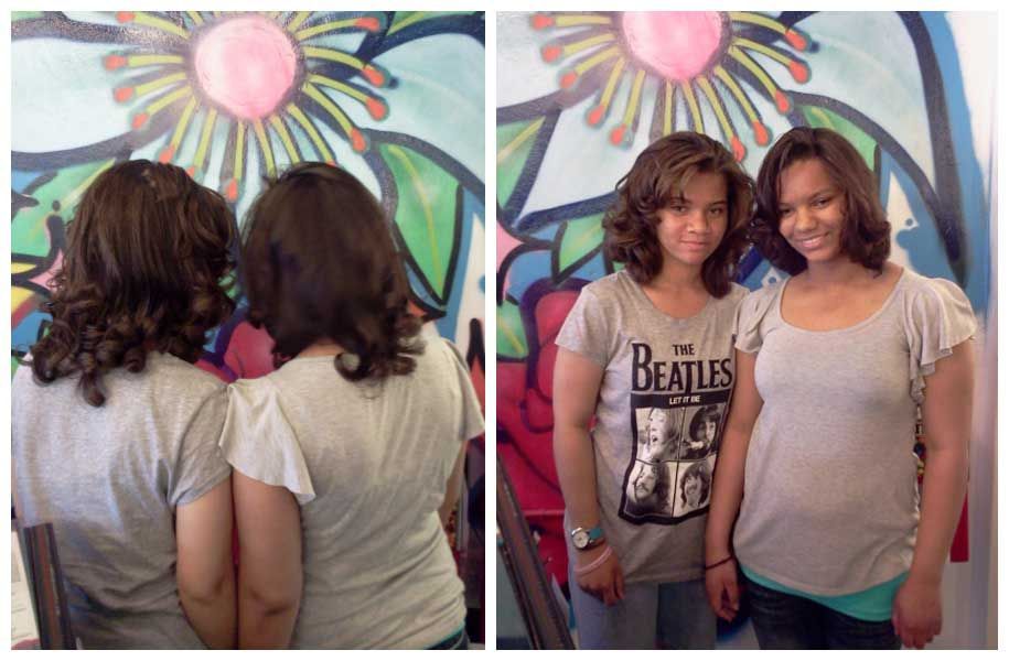 Two women are standing next to each other in front of a mural . one of the women is wearing a beatles shirt.