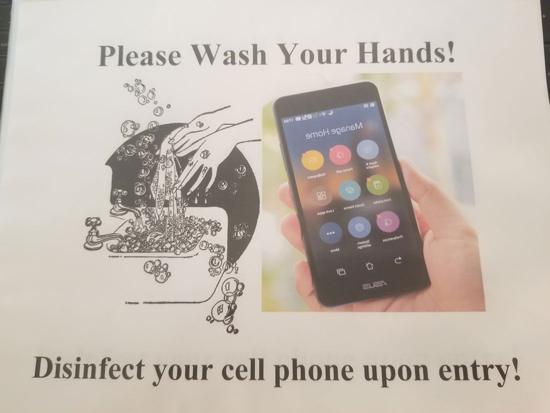 A sign asking people to wash their hands and disinfect their cell phone upon entry