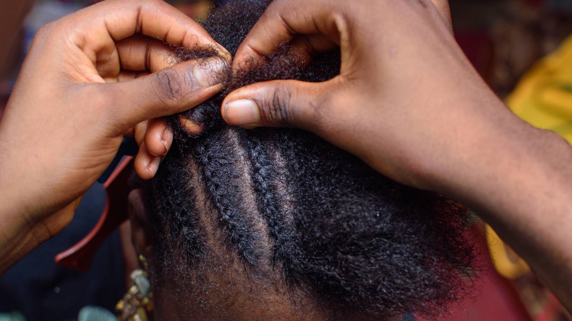 A close up of a person braiding another person 's hair.