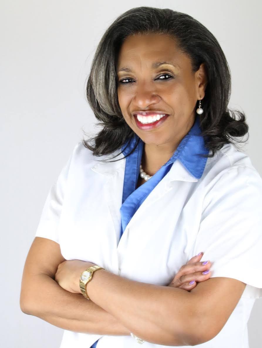 A woman in a white lab coat with her arms crossed smiles for the camera