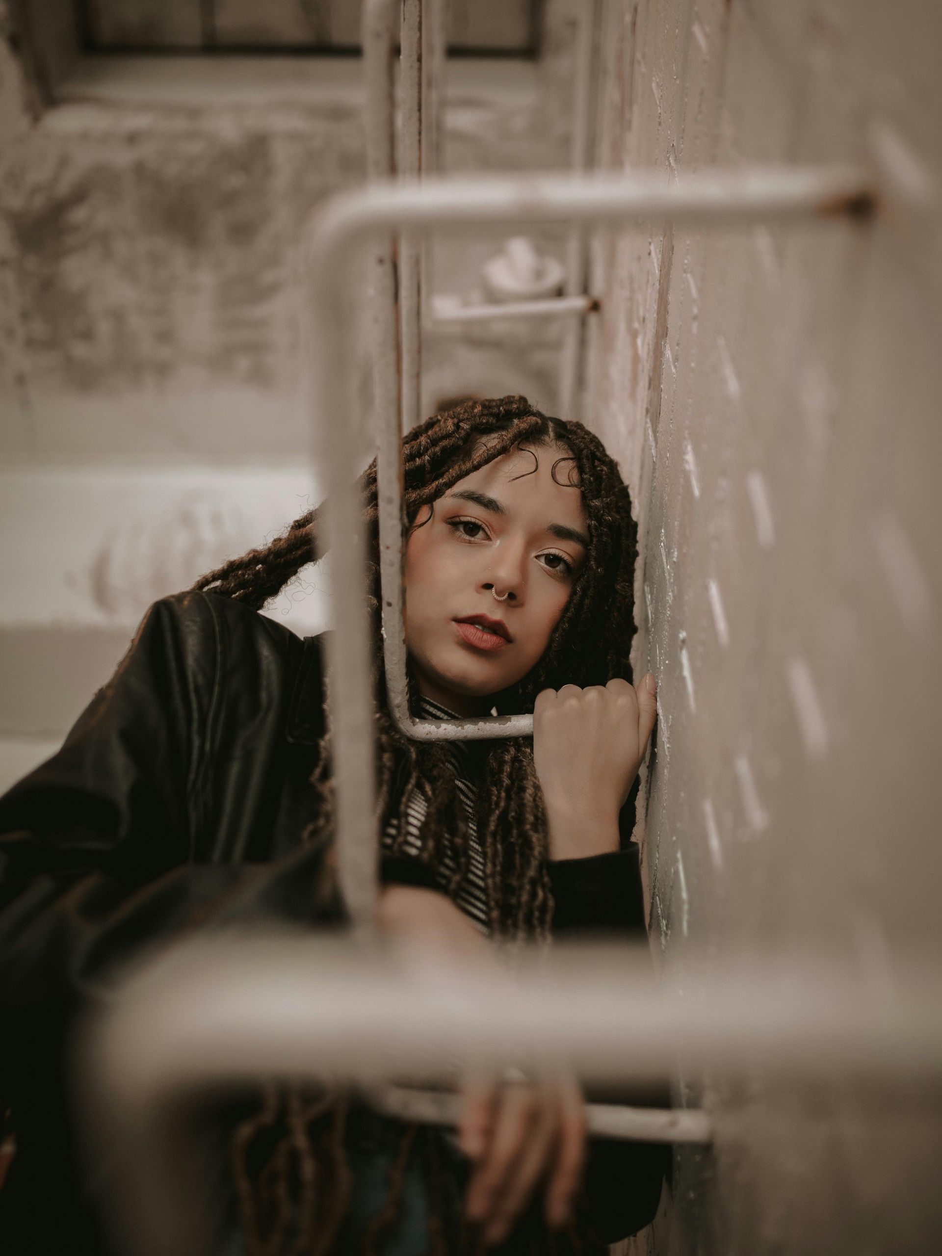 A woman with dreadlocks is leaning against a wall.