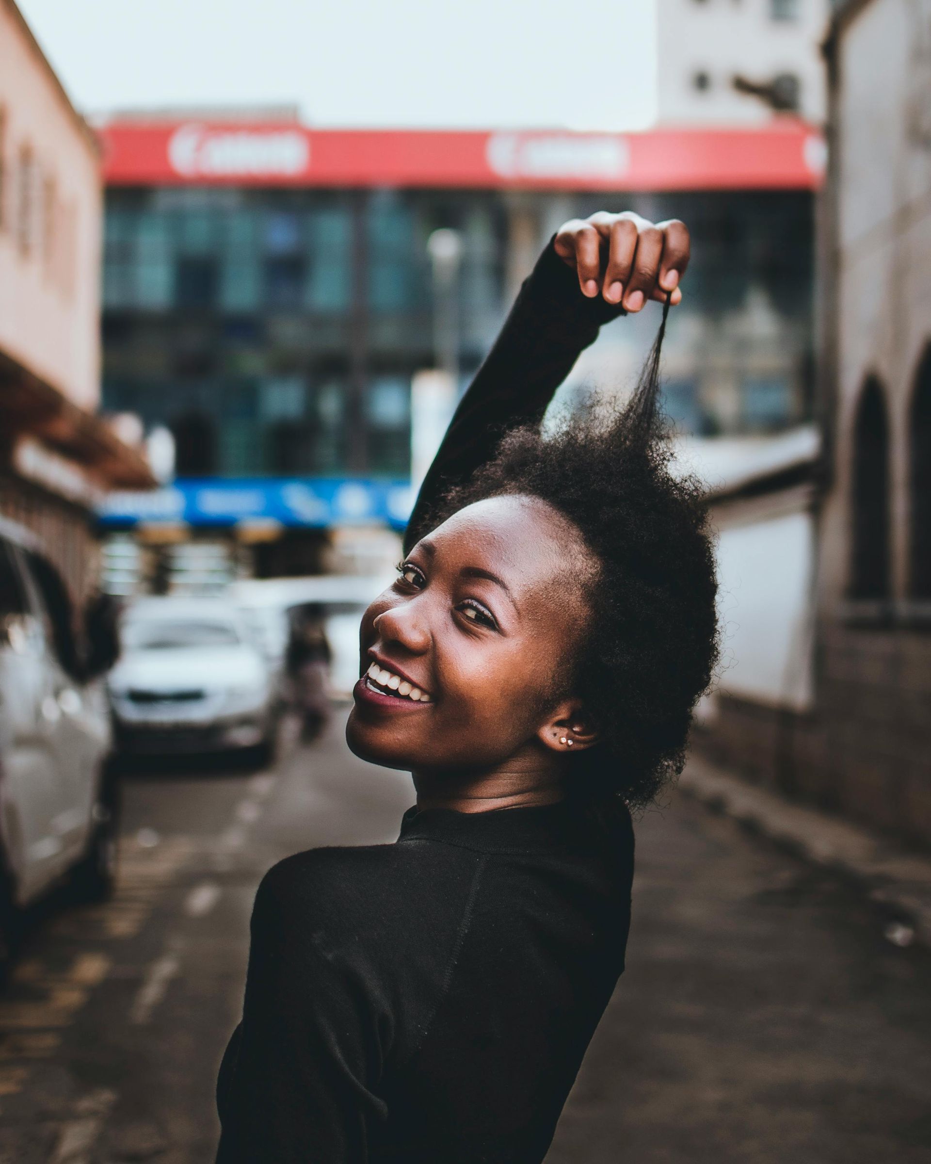 A woman is holding her hair in the air and smiling.