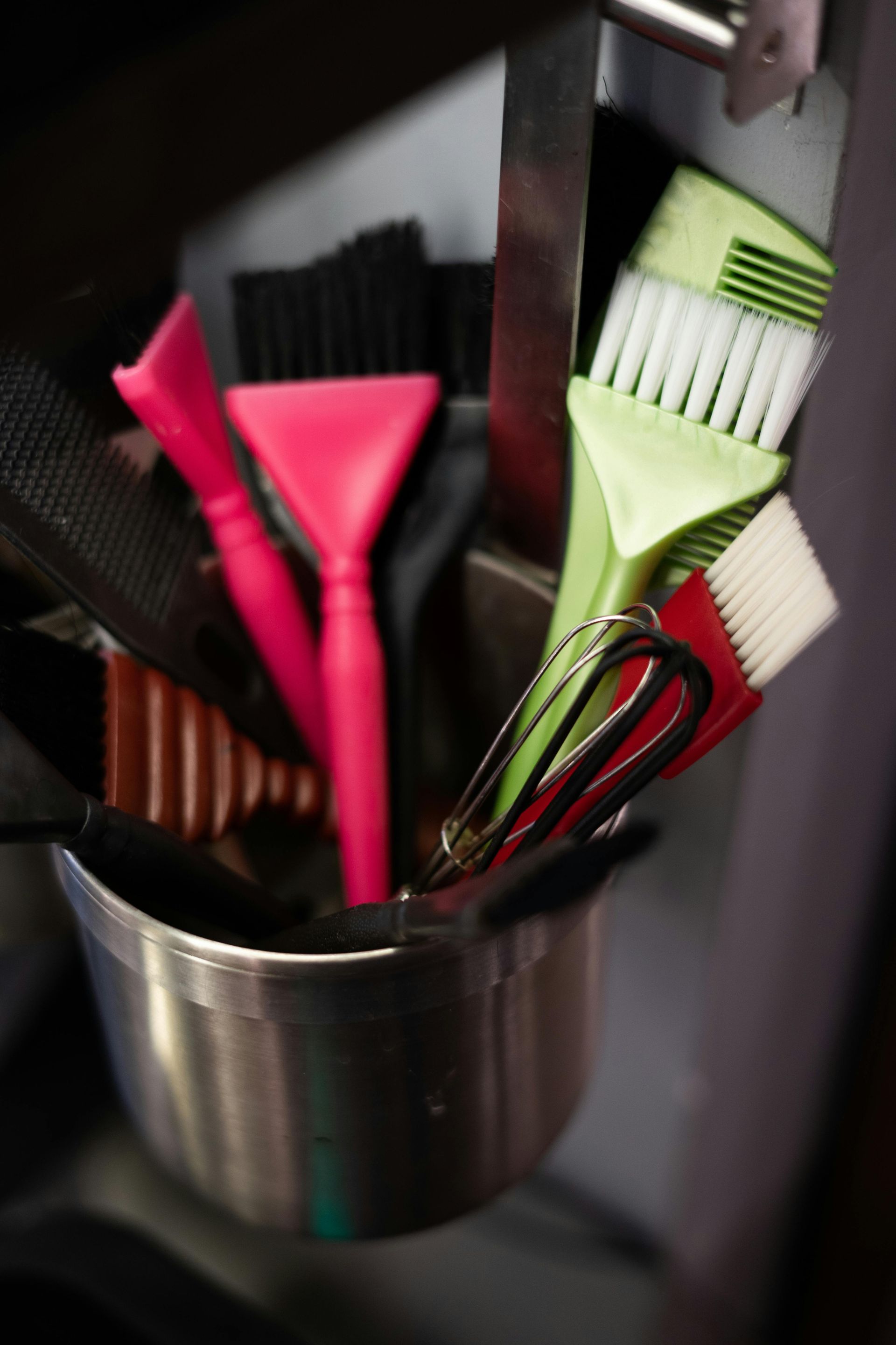 A metal bucket filled with brushes and scissors