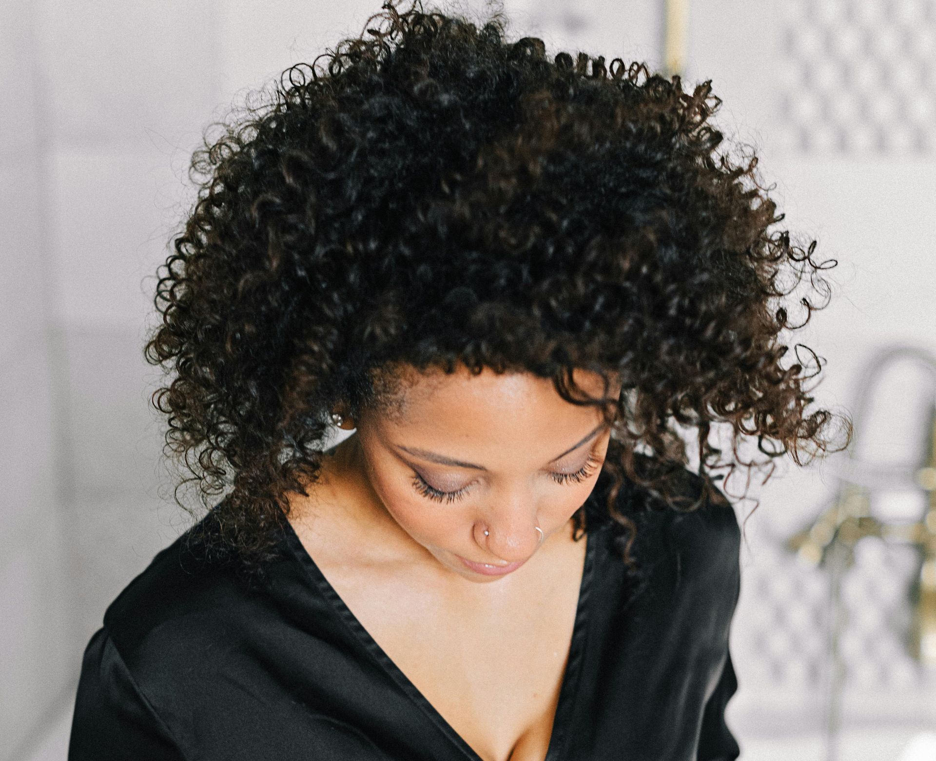 A woman with curly hair is wearing a black shirt
