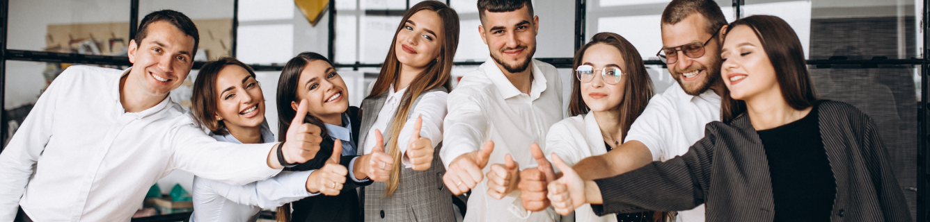 Um grupo de pessoas está próximo um do outro e fazendo sinal de positivo.