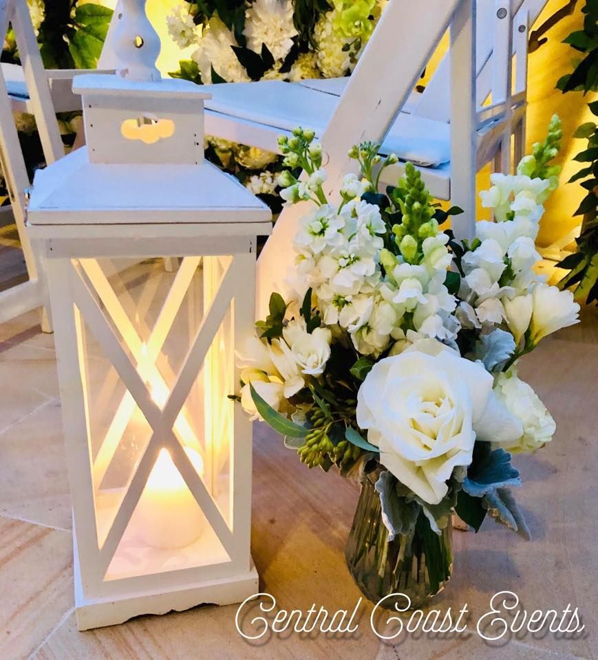 A Vase of White Flowers Sits Next to a White Lantern — Central Coast Events in Berkeley Vale, NSW