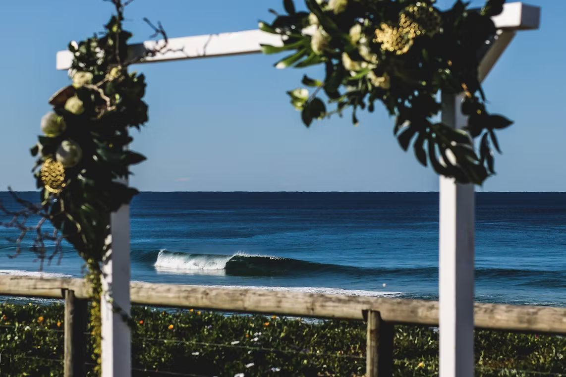A White Arch With Flowers on It is Sitting on the Beach Near the Ocean ― Central Coast Events in Berkeley Vale, NSW