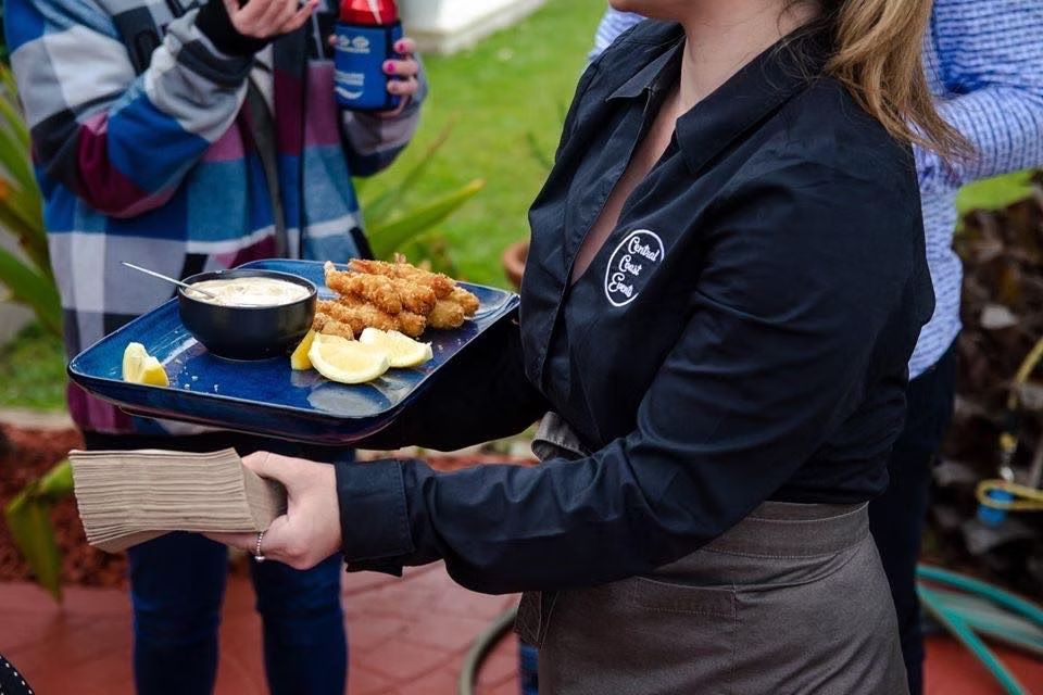 A Woman in a Black Shirt is Holding a Tray of Food ― Central Coast Events in Berkeley Vale, NSW
