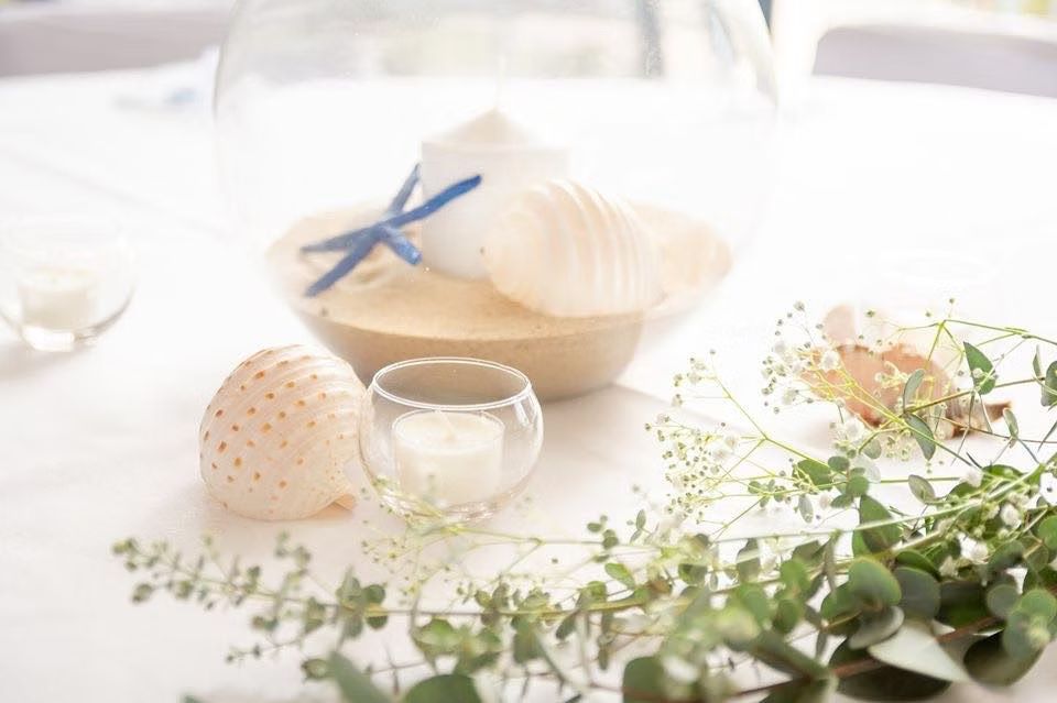 A Table With a Vase Filled With Sand, Seashells and a Candle ― Central Coast Events in Berkeley Vale, NSW