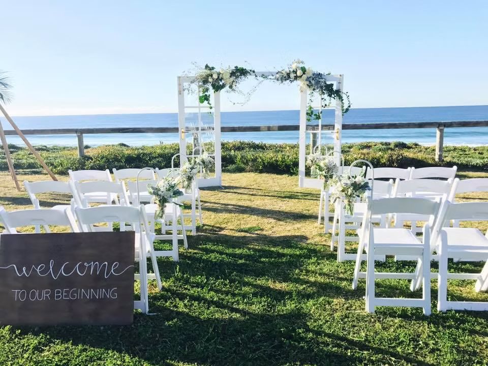 A Wedding Ceremony on the Beach With White Chairs and a Welcome Sign ― Central Coast Events in Berkeley Vale, NSW